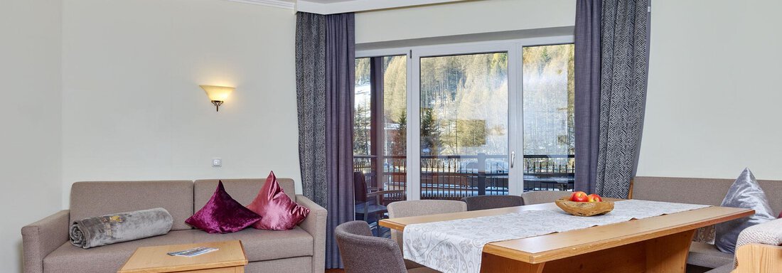 A bright living room with a table and chairs, as well as a cozy couch. The large windows offer a view outside and let in plenty of light. - Alp Resort Tiroler Adler - Sölden