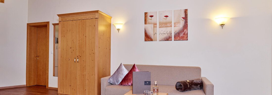 Adler-Suite A bright living space with wooden ceilings and warm light. A cozy sofa, a table, and decorative elements create an inviting atmosphere. - Alp Resort Tiroler Adler - Sölden