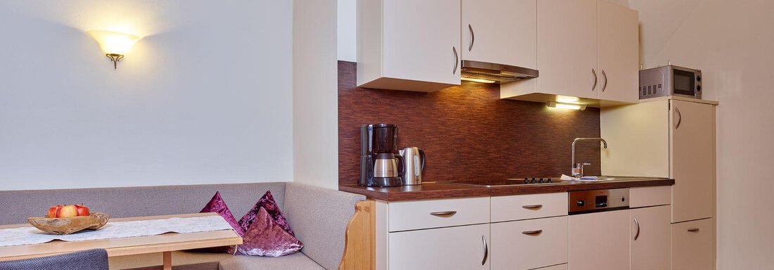 A modern kitchen with a wooden ceiling and light cabinets. The dining area is cozy and invitingly furnished. - Alp Resort Tiroler Adler - Sölden
