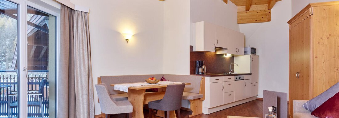 A cozy apartment with a wooden ceiling and large windows. The living area is bright and welcoming, featuring a dining table and a modern kitchen. - Alp Resort Tiroler Adler - Sölden