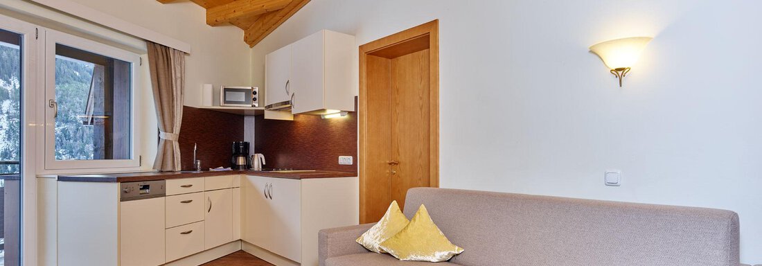 A cozy living room with a wooden ceiling and modern furniture. The kitchen is open and well-equipped, perfect for relaxed days. - Alp Resort Tiroler Adler - Sölden