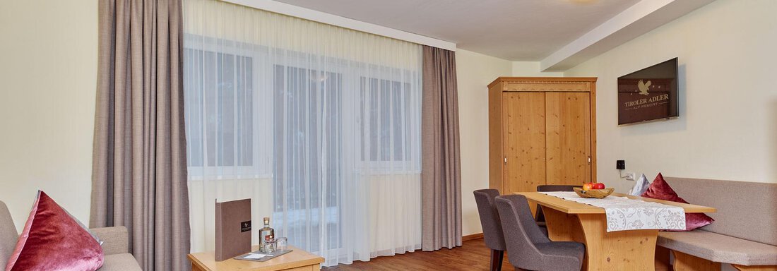 Murmele-Suite A bright and modern living room with hardwood floors and large windows. There is a seating area with a sofa, table, and chairs, as well as decorative elements. - Alp Resort Tiroler Adler - Sölden