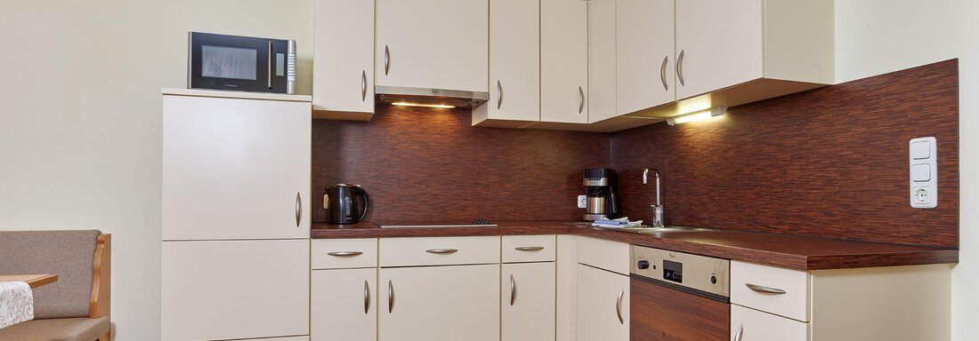 A modern kitchen with bright cabinets and wooden surfaces. It is equipped with a microwave, coffee maker, and dishwasher. - Alp Resort Tiroler Adler - Sölden