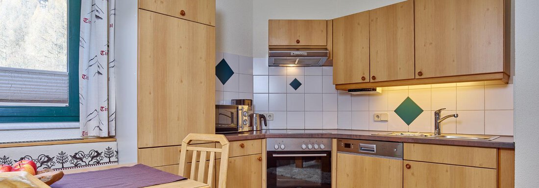 Andreus-Suite A modern kitchen with wooden cabinets and a dining table. It is bright and well-equipped. - Alp Resort Tiroler Adler - Sölden