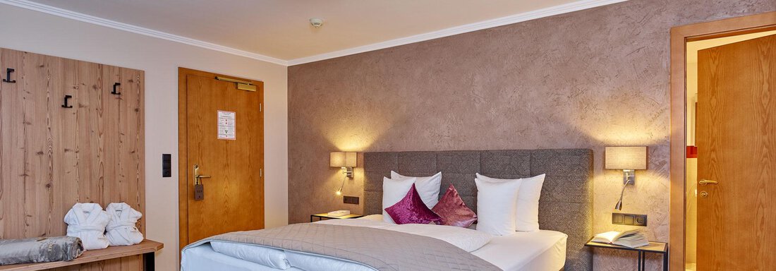 A modern room with a double bed and soft lighting. The decor includes wood and fabric elements that create a cozy atmosphere. - Alp Resort Tiroler Adler - Sölden