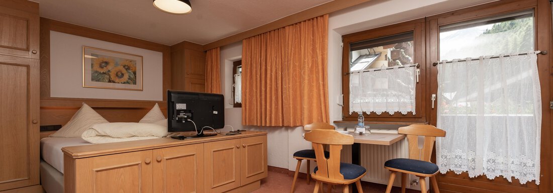 Zimmerfotos-38 A cozy room with a double bed and a table for two people. Large windows provide plenty of daylight and a pleasant atmosphere. - Alpenliebe - Sölden