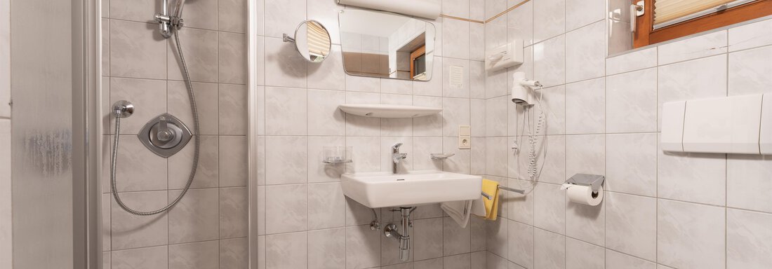 A modern bathroom with bright tiles and a shower. There is a sink, a toilet, and a window with a view outside. - Alpenliebe - Sölden