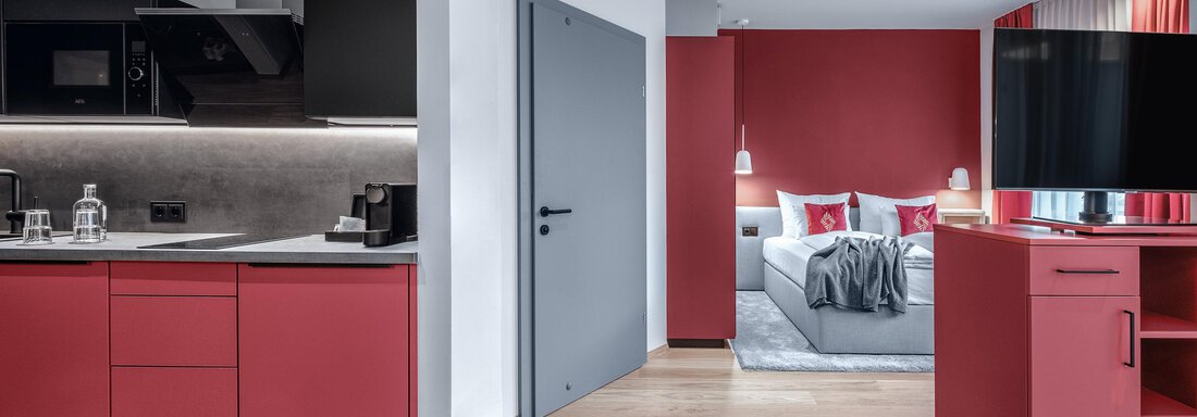 Apartment-resort-im-oetztal -the-secret-soelden-Sm A modern room with an open kitchenette and red accents. The area is stylishly furnished and offers a cozy atmosphere. - AlpenParks The Secret Sölden - Sölden