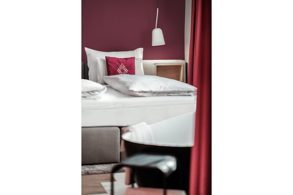 A stylish bedroom with a comfortable bed and a modern bathtub. The walls are painted in a warm shade of purple, and there are cozy decorative elements. - AlpenParks The Secret Sölden - Sölden