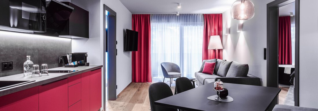 Modern apartment with red kitchen unit and stylish dining area. Cozy living room with plenty of light and modern furniture. - AlpenParks The Secret Sölden - Sölden