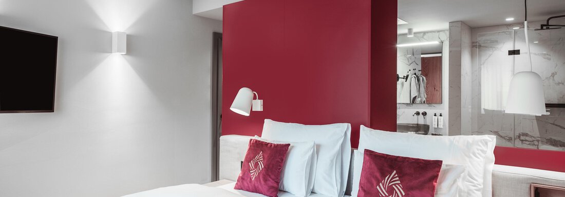 A modern hotel room with a double bed and red accents. The room design is bright and inviting. - AlpenParks The Secret Sölden - Sölden