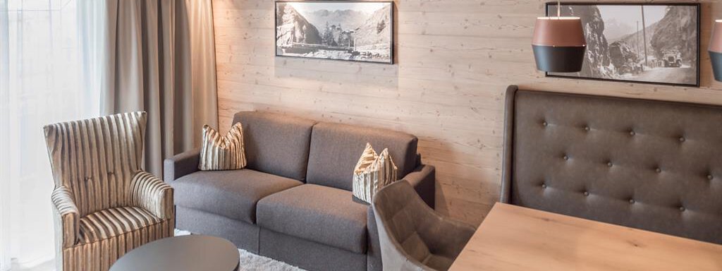 A modern living room with a cozy sofa, two seating areas, and a wooden table. Bright colors and wood paneling create an inviting atmosphere. - AlpenParks The Secret Sölden - Sölden
