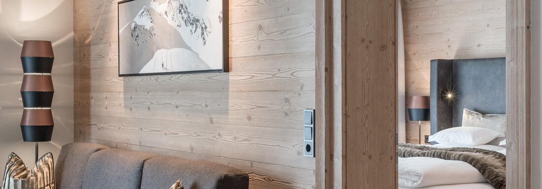 A modern hotel room with wooden walls and an elegant decor. The room is cozy and well-lit, with a view of a piece of artwork. - AlpenParks The Secret Sölden - Sölden