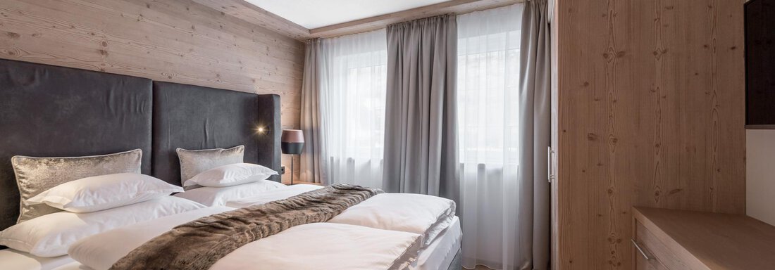 LARGE SECRET A cozy bedroom with a large double bed and elegant bedding. The wood paneling and soft lighting create a warm atmosphere. - AlpenParks The Secret Sölden - Sölden