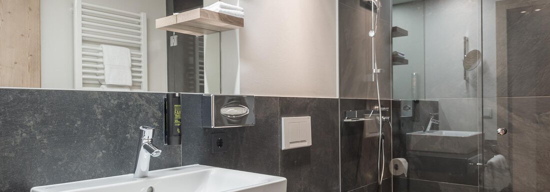 A modern bathroom with elegant fixtures. The shower is separated by glass walls and the furnishings are simple and stylish. - AlpenParks The Secret Sölden - Sölden
