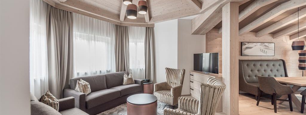 EXTRA LARGE PLUS SECRET A modern living room with wooden details and a cozy ambiance. The furnishings include a comfy couch and stylish armchairs around a round table. - AlpenParks The Secret Sölden - Sölden