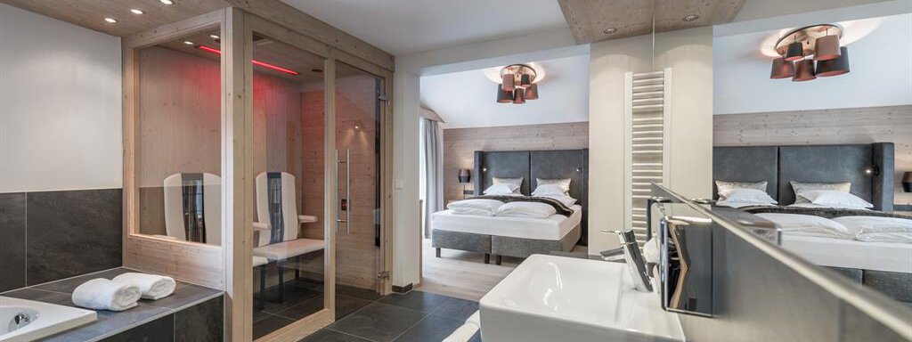 A modern hotel room with two beds and elegant furnishings. The combination of wood and stone creates a relaxing atmosphere, complemented by a sauna and a stylish bathroom. - AlpenParks The Secret Sölden - Sölden