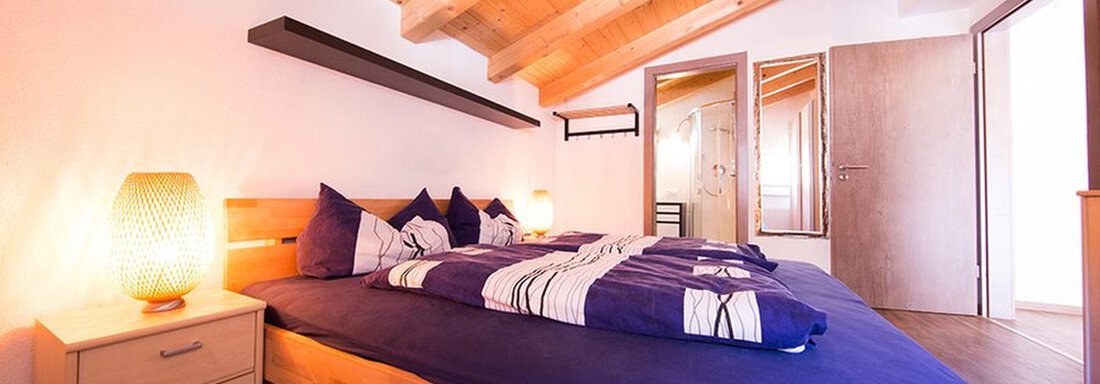 A cozy bedroom with two single beds and modern wooden elements. The warm colors and the wooden bridge create an inviting atmosphere. - Alpensweet - Sölden