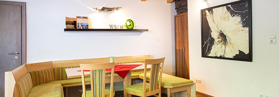 A cozy dining area with a wooden ceiling and a round bench. A modern piece of art hangs on the wall. - Alpensweet - Sölden