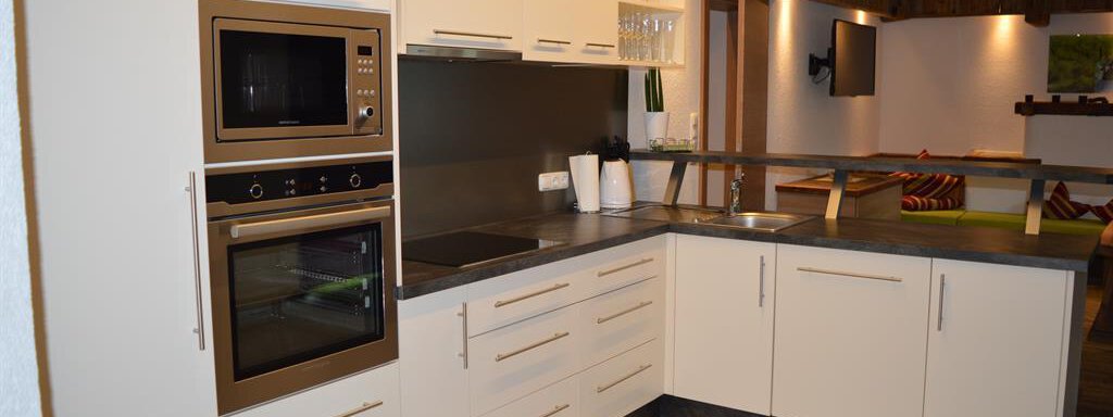 A modern kitchen with bright cabinets and elegant appliances. The space is well-lit and neatly arranged. - Am Trogwohl - Sölden