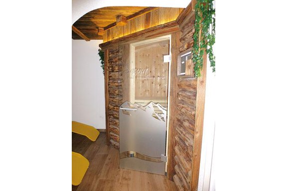 A modern sauna area with wood paneling and a stylish glass door. The furnishings convey a warm and inviting atmosphere. - Am Trogwohl - Sölden