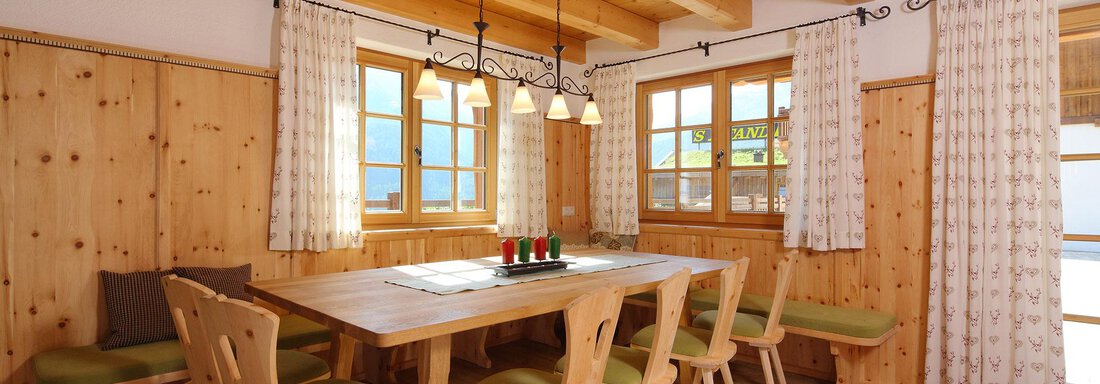 A cozy dining area with wood paneling and a large table. The windows let in plenty of light and the chairs are in soft colors. - Andis Almdorf - Sölden