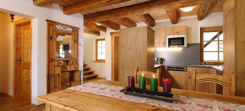 A cozy living space with wooden decor and a dining area. The kitchen is modern and well-equipped, and there are large windows that let in plenty of light. - Andis Almdorf - Sölden