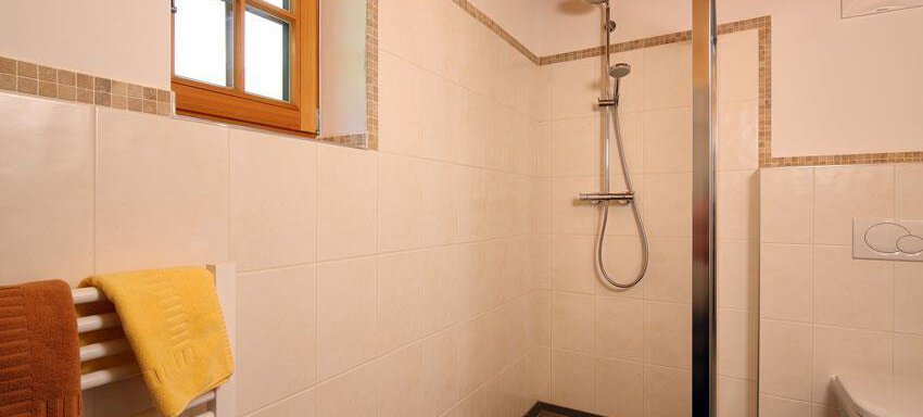 A modern bathroom with a shower and tiles. The walls are light and there is a window for natural light. - Andis Almdorf - Sölden