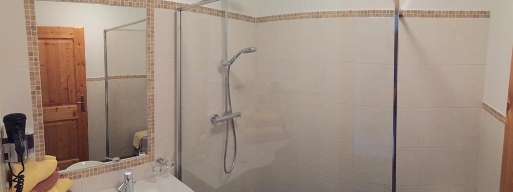 A modern bathroom with a shower cabin and a sink. Towels in yellow and purple are ready. - Andis Almdorf - Sölden