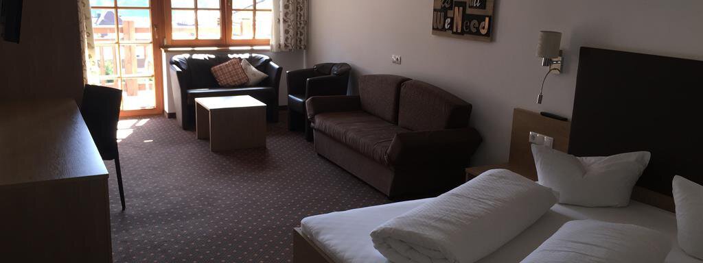 A cozy room with a double bed, a sofa, and a table.  
Large windows provide plenty of daylight and access to the balcony. - Andis Almdorf - Sölden