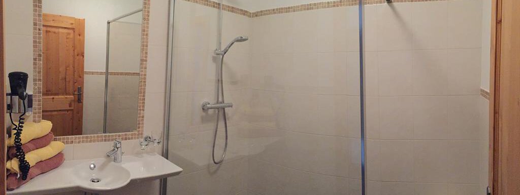 A modern bathroom with a walk-in shower and a sink. Fresh towels are ready on a shelf. - Andis Almdorf - Sölden