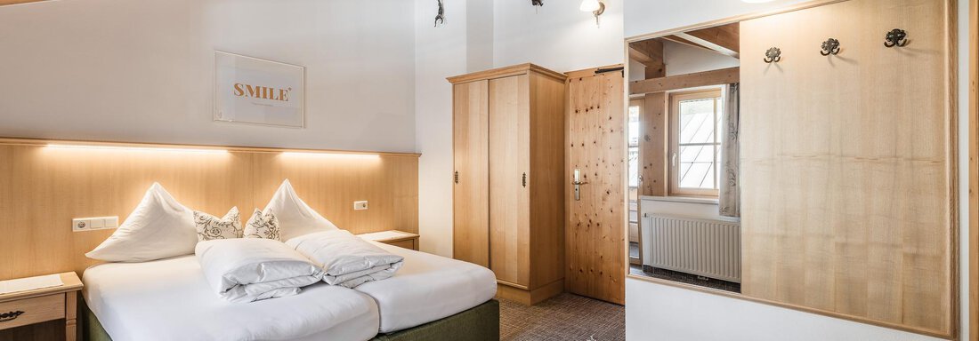 A modern room with a double bed and wooden elements. The lighting conditions are bright and inviting. - Andre Arnold - Boutique Hotel - Sölden