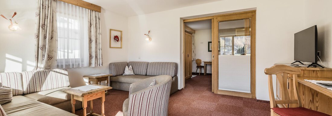 A cozy living room with a sofa and a table. The room is bright and invites relaxation. - Andre Arnold - Boutique Hotel - Sölden