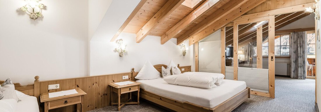 A cozy bedroom with a wooden beam ceiling and two beds. The decor is modern and rustic, ideal for a relaxing stay. - Andre Arnold - Boutique Hotel - Sölden