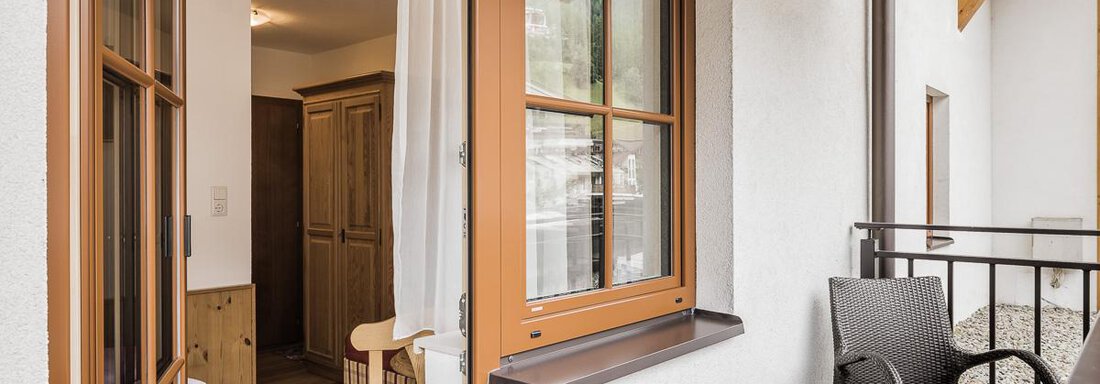 A cozy balcony with a table and two chairs. The view shows an inviting interior and a beautiful outlook outside. - Andre Arnold - Boutique Hotel - Sölden
