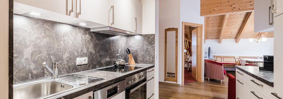 A modern kitchen with elegant furniture and wooden ceilings. It is bright and cozy, ideal for cooking and lingering. - Andre Arnold - Boutique Hotel - Sölden