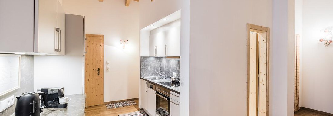 A modern kitchen with wooden details and practical appliances. The space has an open layout and soft lighting that creates a cozy atmosphere. - Andre Arnold - Boutique Hotel - Sölden