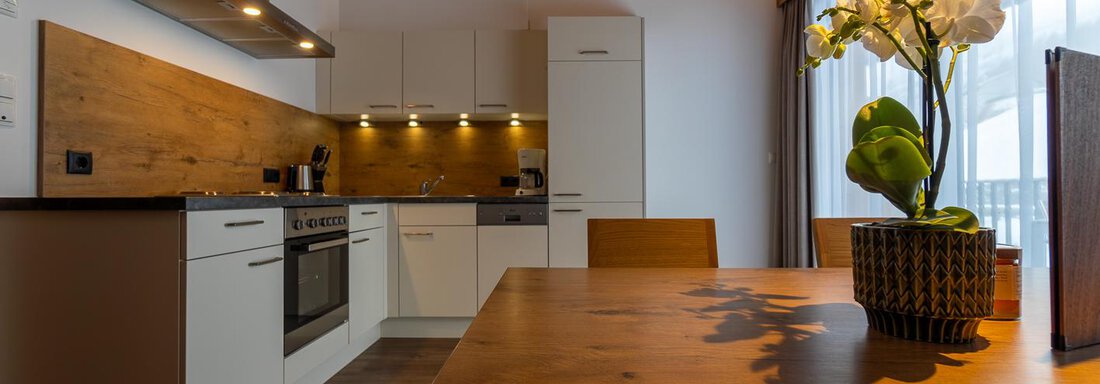Fotos Apartment A4-19 Modern kitchen with wooden details and a bright dining table. A floral arrangement brings color to the room. - Anraitl Appartements Sölden - Sölden