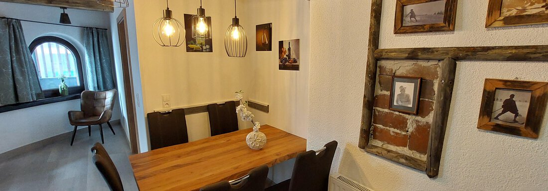 A cozy dining area with a wooden table and modern chairs. Pictures hang on the walls and the lighting creates a pleasant atmosphere. - Apart 77 - Sölden