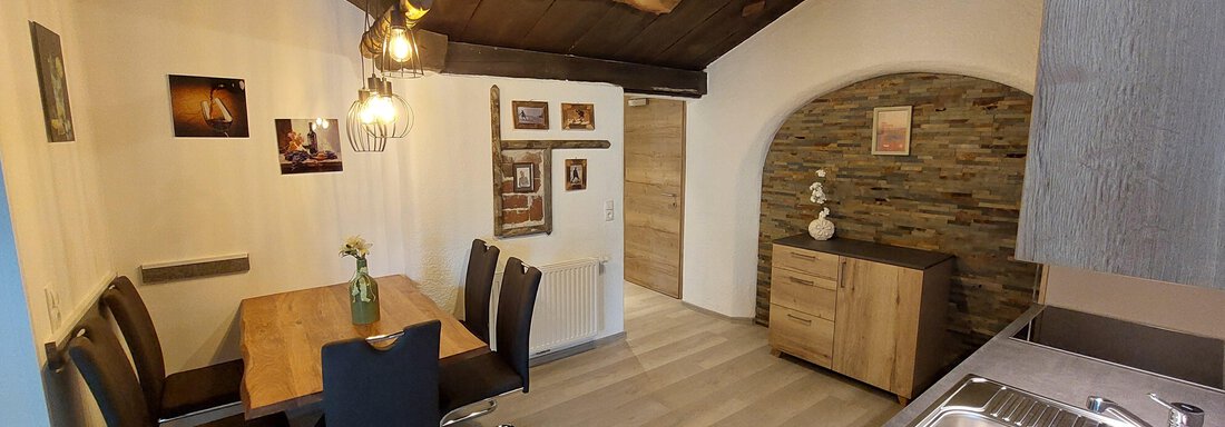 A cozy dining area with a wooden table and modern chairs. The kitchen is simple and functional, with a warm atmosphere created by wooden details. - Apart 77 - Sölden