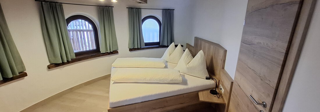 A bright room with two beds and large windows. The decor is modern with wooden walls and green curtains. - Apart 77 - Sölden