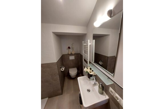 A modern bathroom with neutral colors. It features a sink, a mirror, and a toilet. - Apart 77 - Sölden
