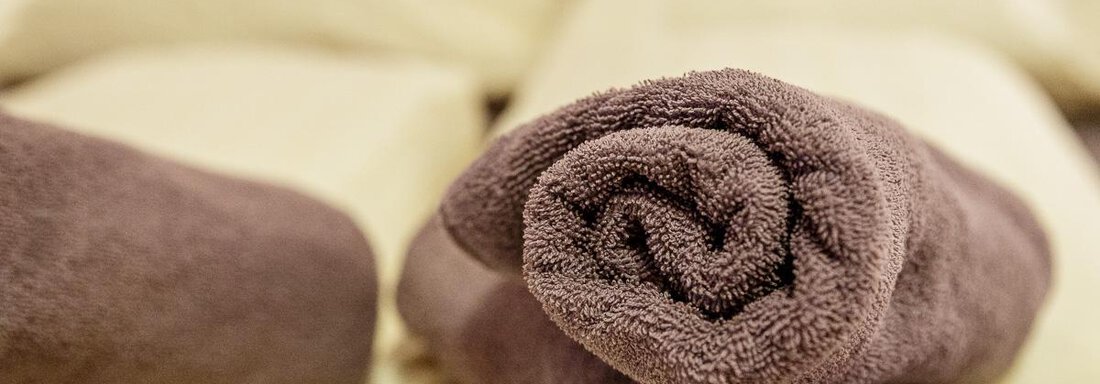A rolled towel on a bed with bright pillows. The atmosphere feels cozy and inviting. - Apart Garni Enzian - Sölden