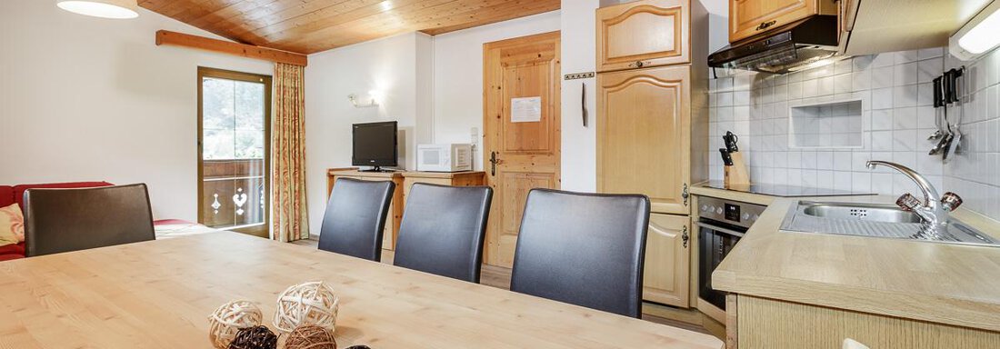 Wohnküche Gaislachkogel | © RudiWyhlidal A modern kitchen with a large wooden table and black chairs. The room has a cozy, warm wood decor and plenty of natural light. - Apart Garni Enzian - Sölden