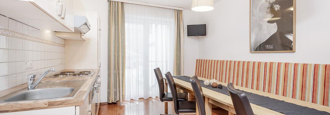 Wohnküche Nederkogel | © RudiWyhlidal A modern kitchen unit with a large dining table and chairs. The room has bright lighting and friendly colors. - Apart Garni Enzian - Sölden