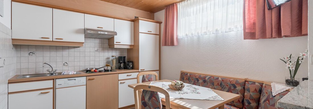 Küche A bright kitchen with wooden ceilings and modern furniture. The dining area features a table and a cozy seating area. - Apart Wiesengrund - Sölden