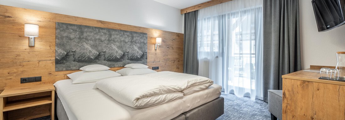 Doppelzimmer | © Johannes Brunner (CC C) A modern hotel room with a large box spring bed. The room features a television and a balcony. - Apart Hotel Garni Alt Kaisers - Sölden
