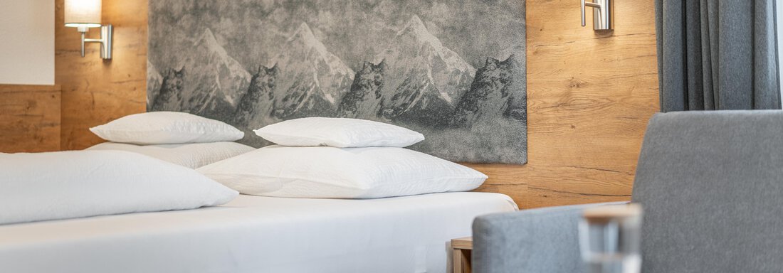 A modern hotel room with a comfortable box spring bed and a stylish wall mural. The cozy decor invites relaxation. - Apart Hotel Garni Alt Kaisers - Sölden