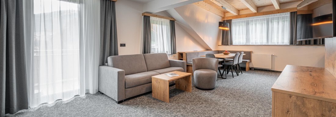A spacious living room with modern furniture and large windows. Bright curtains create a friendly atmosphere. - Apart Hotel Garni Alt Kaisers - Sölden