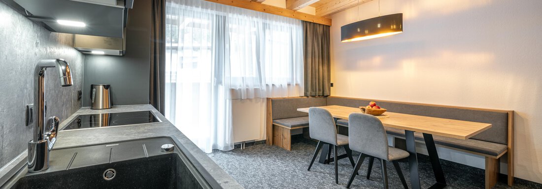 Modern kitchen with a view of a dining area. Bright colors and wooden details create an inviting atmosphere. - Apart Hotel Garni Alt Kaisers - Sölden